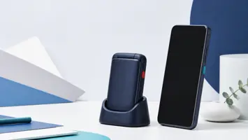 Lukket klapptelefon i ladestasjon ved siden av en smarttelefon med store sideknapper